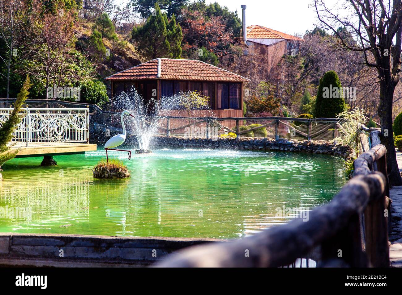 Lago con trote in montagna. Allevamento di trote. C'è una fontana nel lago. Vicino all'edificio di un ristorante e di un hotel Foto Stock