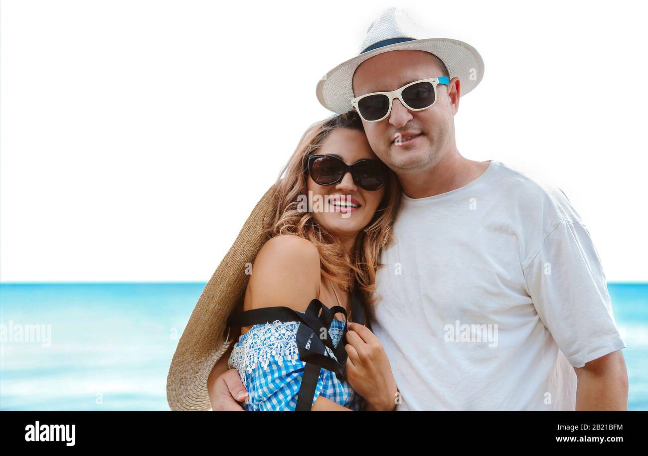 Contenuto riposo uomo e donna in occhiali da sole e cappelli sorridenti  abbracciando e guardando la fotocamera con il mare blu e cielo sullo sfondo  Foto stock - Alamy