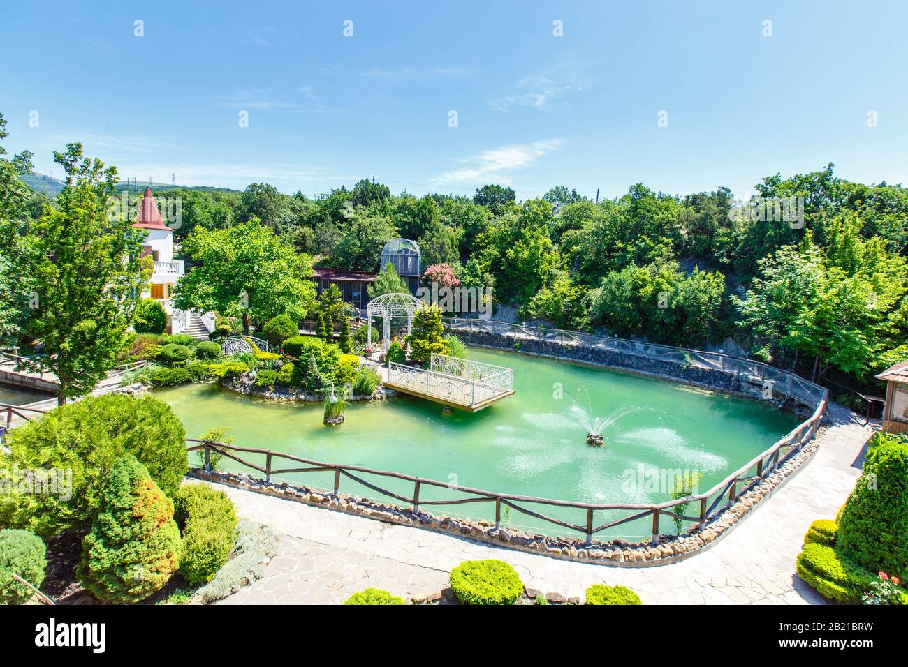 Lago con trote in montagna. Allevamento di trote. C'è una fontana nel lago. Vicino all'edificio di un ristorante e di un hotel Foto Stock