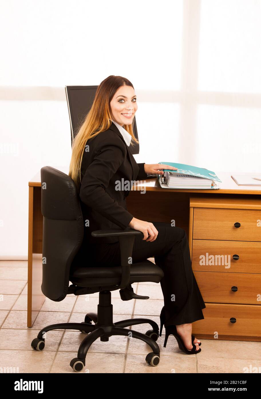 Giovane donna di affari con i dati audaci di controllo della cartella alla sua scrivania in ufficio Foto Stock