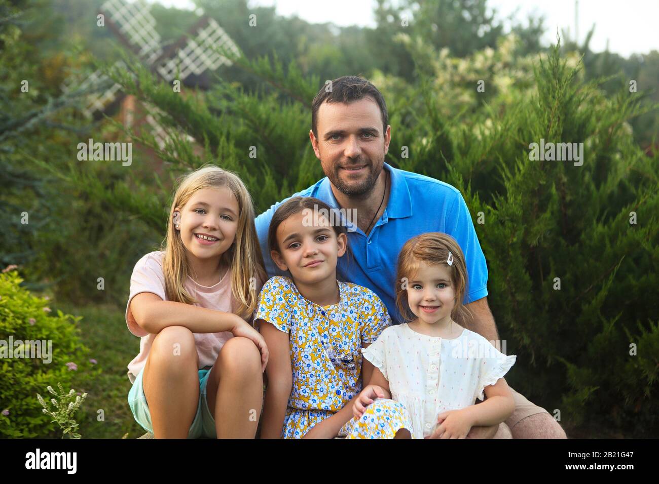 Allegro uomo adulto con le figlie mentre trascorrono il tempo in giardino verde insieme Foto Stock