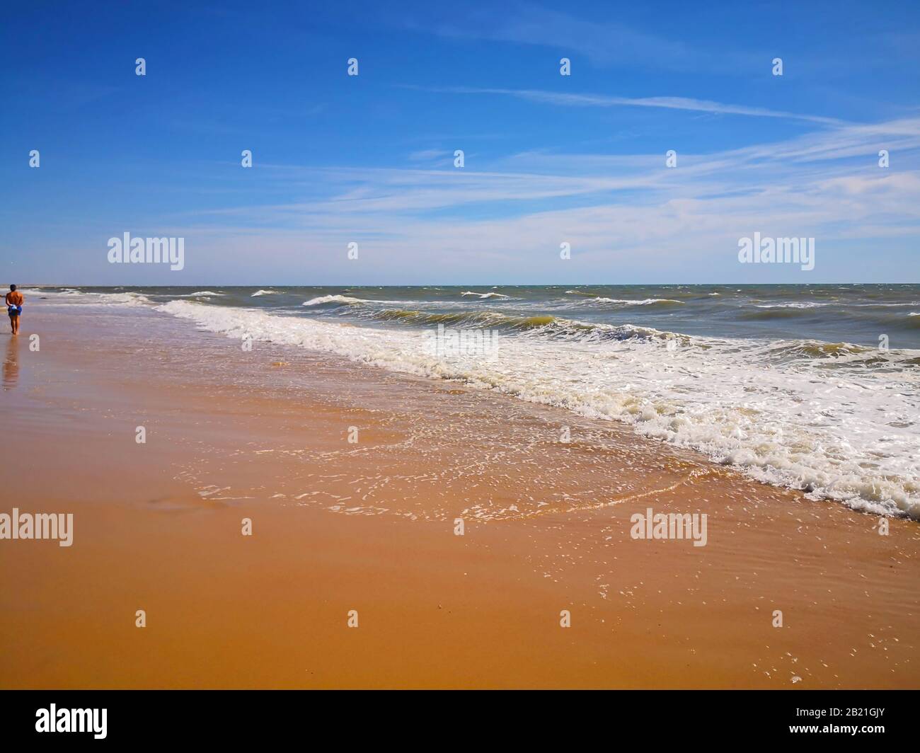 Spiaggia sabbiosa con vie, cielo blu. Giornata di sole a Matalascanas, Spagna Foto Stock