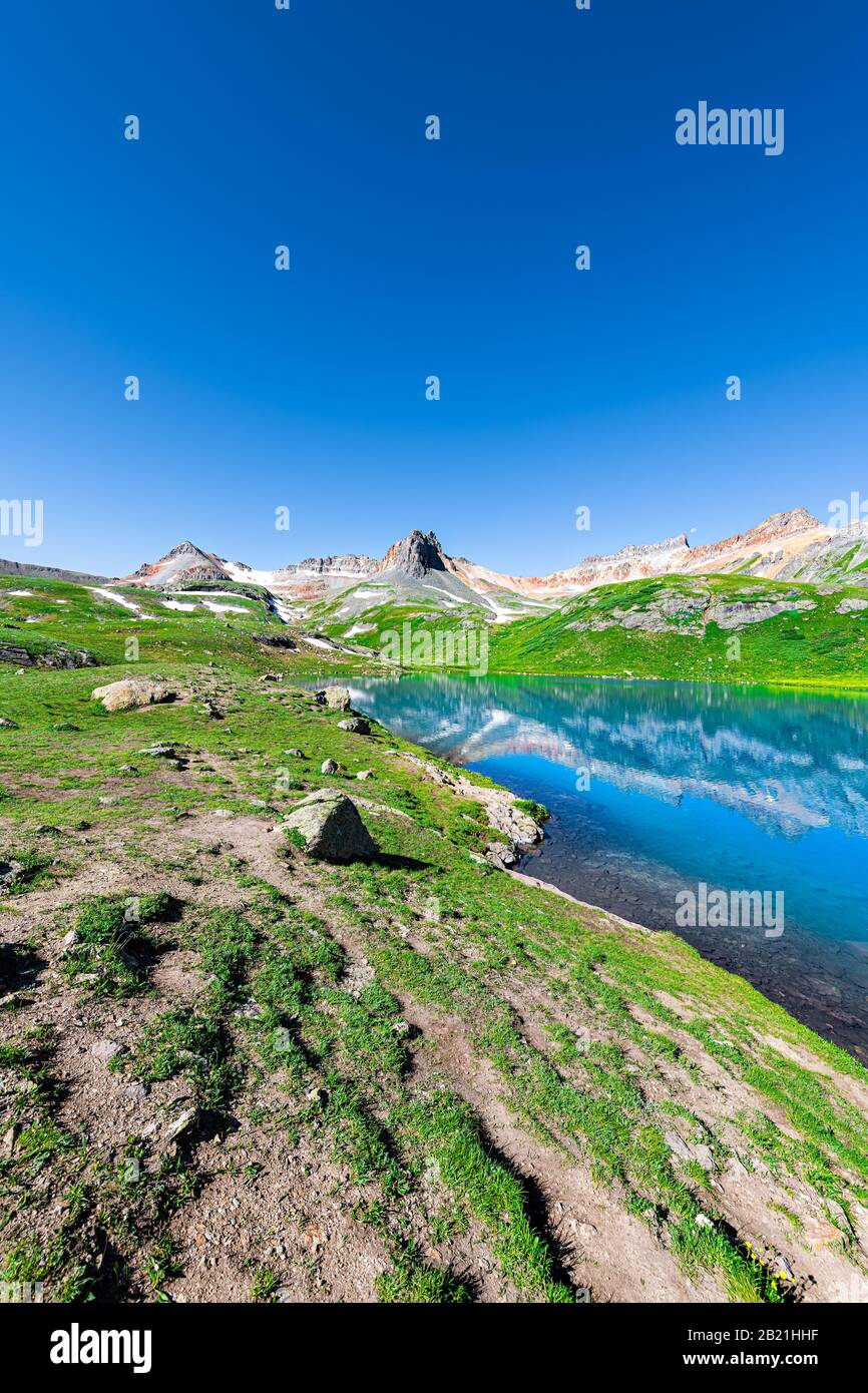 Vista verticale ad ampio angolo del lago di ghiaccio turchese vicino a Silverton, Colorado, sulla cima rocciosa della montagna e la neve nell'agosto 2019 estate Foto Stock