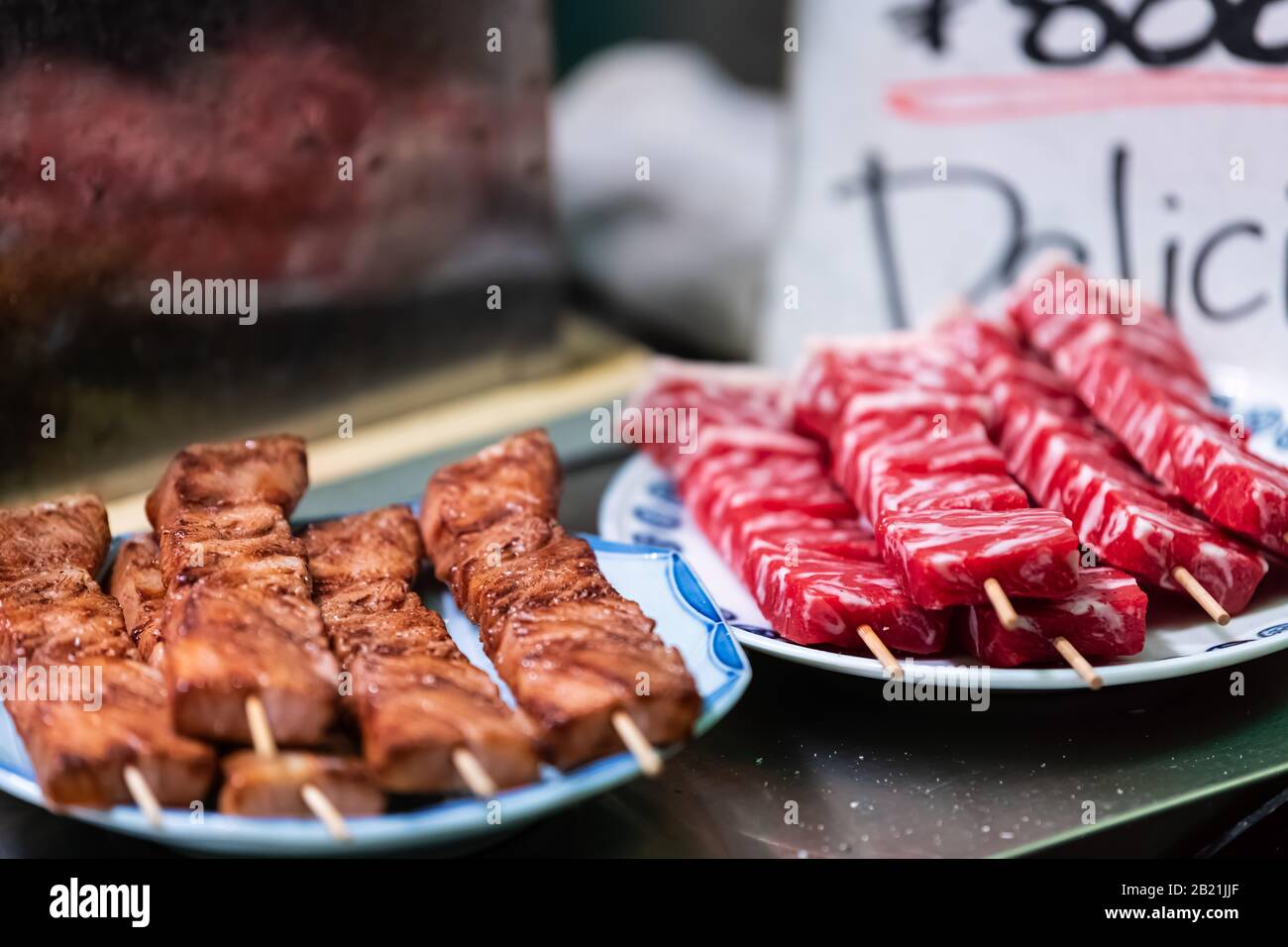 Kyoto, Giappone Nishiki negozio di mercato alimentare venditore di cibo che vendono wagyu kobe manzo crudo e cotto su spiedino display Foto Stock