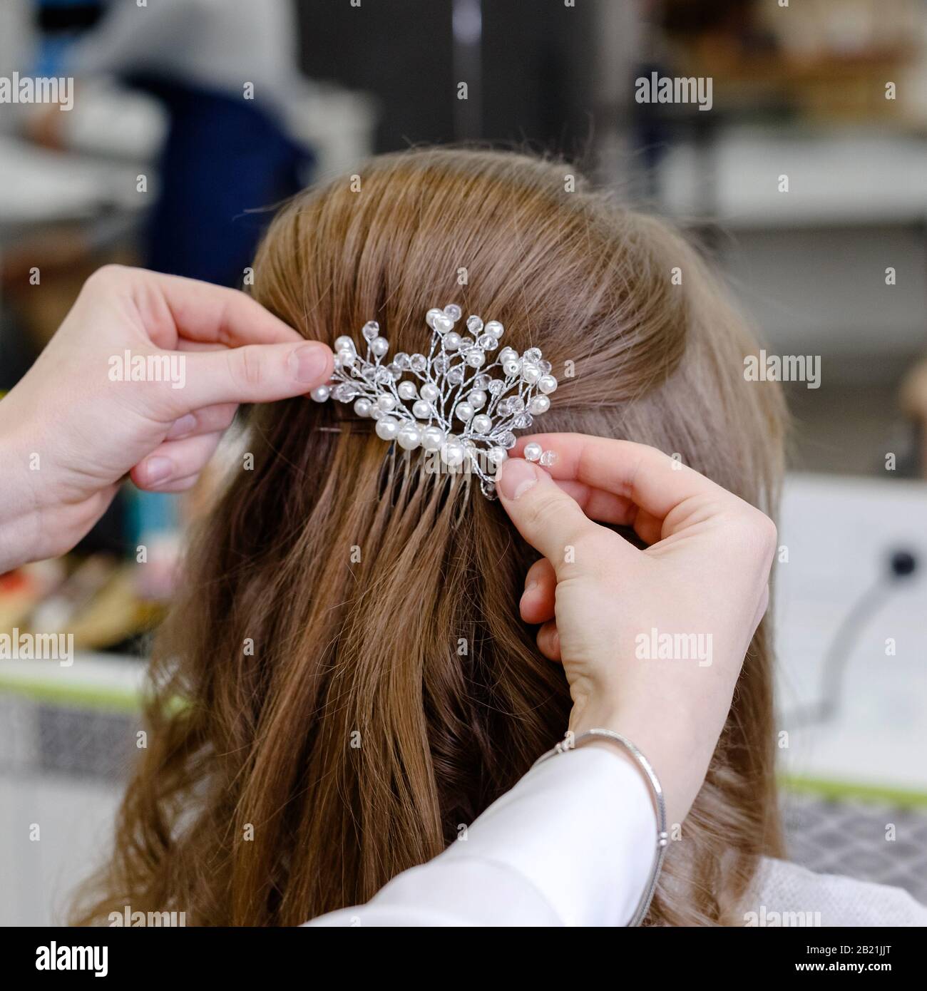 Vista posteriore a pettinatura con tornante. Parrucchiere che fa acconciatura di nozze a donna bionda capelli con capelli lunghi in salone di bellezza. Cura professionale dei capelli Foto Stock