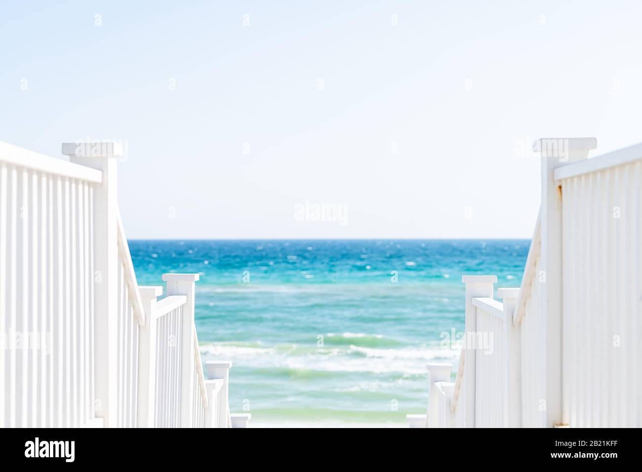 Lungomare, Florida bianca ringhiera scalinata in legno passerella giù vista dell'architettura sulla spiaggia oceano vista sfondo durante la giornata di sole e orizzonte Foto Stock