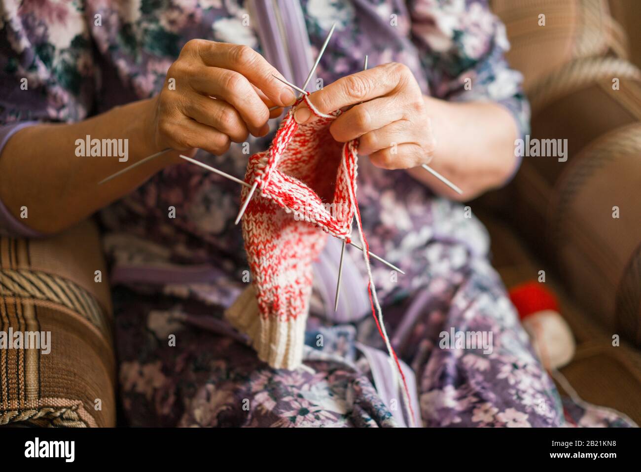 Una donna anziana sta lavorando alcuni calzini Foto Stock