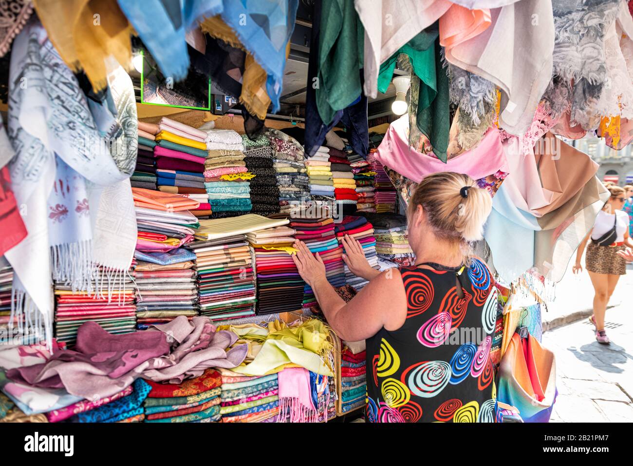 Firenze, Italia - 30 agosto 2018: Donna che acquista molte sciarpe colorati colori vivaci appesi in mostra nel mercato della strada dello shopping a Firenze, in Toscana Foto Stock