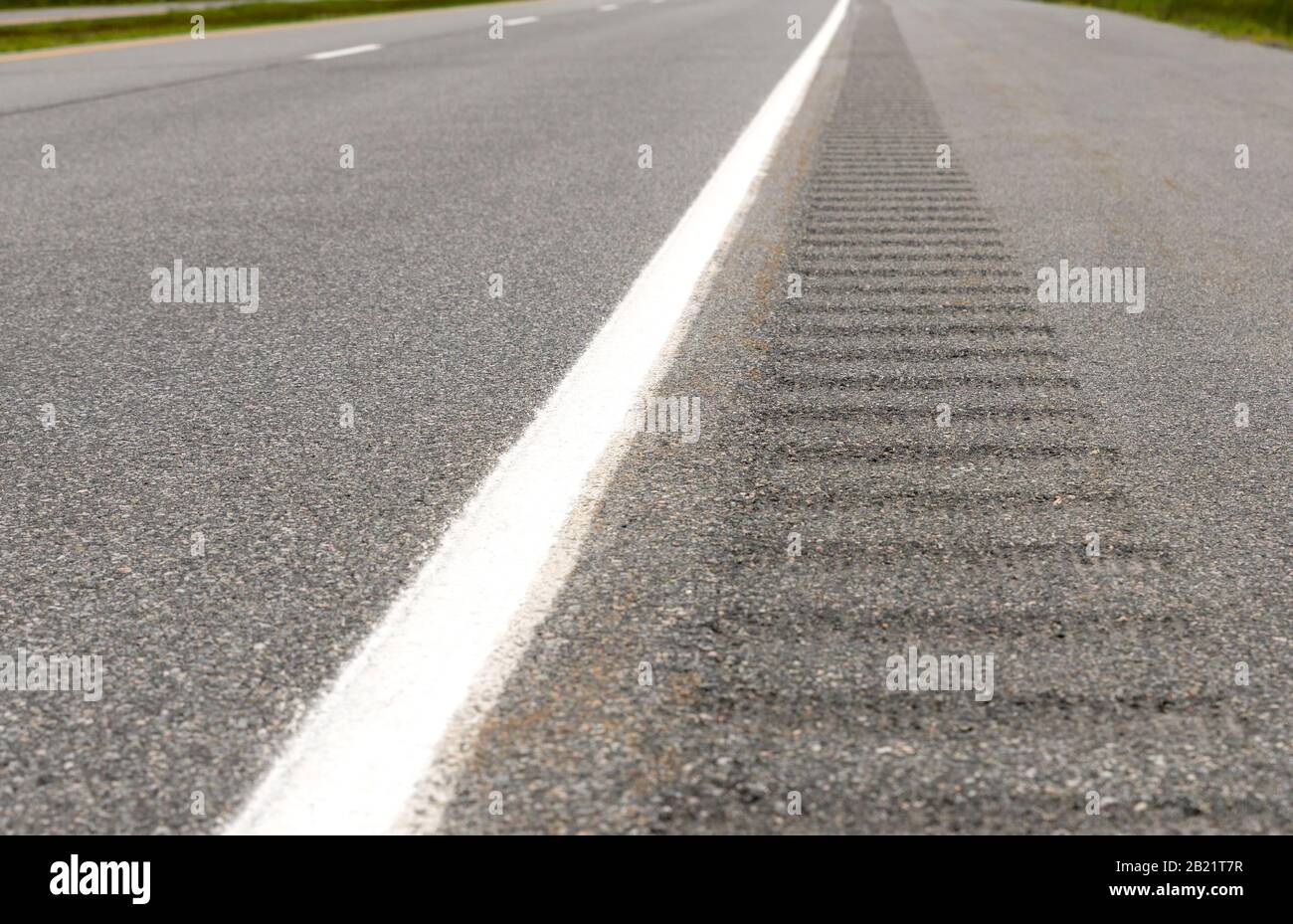La striscia rumble sul lato di un'autostrada, La striscia consiste di buche poco profonde nella spalla pavimentata che vibrano un veicolo se attraversa la linea. Foto Stock