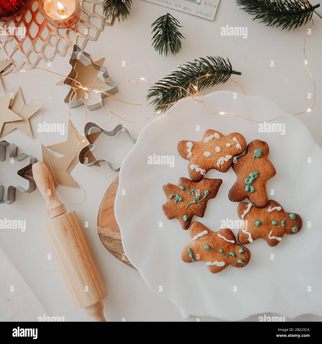 Buffo biscotto fatto in casa sotto forma di albero di Natale, fiocchi di neve e un uomo in un piatto bianco, su un tavolo bianco con perno di rotolamento in legno, Natale tre Foto Stock