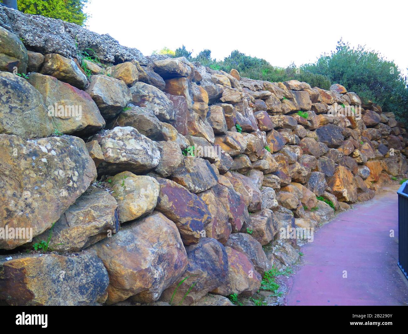Parete di ritegno da ruvida dei blocchi di granito in strada residenziale di Alora, Andalusia Foto Stock