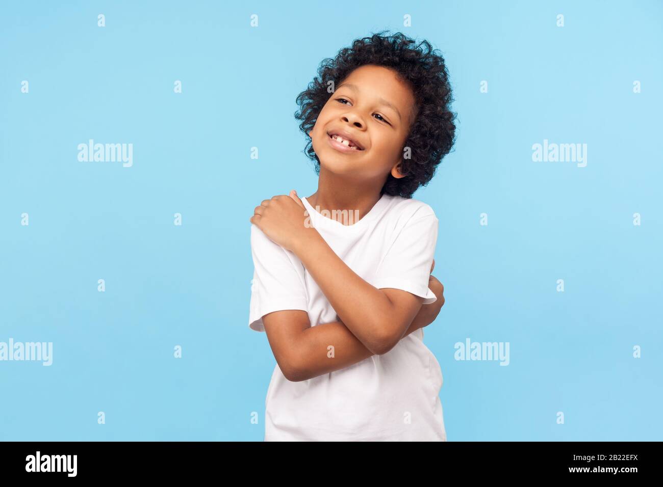 Mi piace. Ritratto di adorabile ragazzino ottimista con ricci che si abbracciano e sorridendo, egoista sicuro di sé bambino con sé positivo Foto Stock