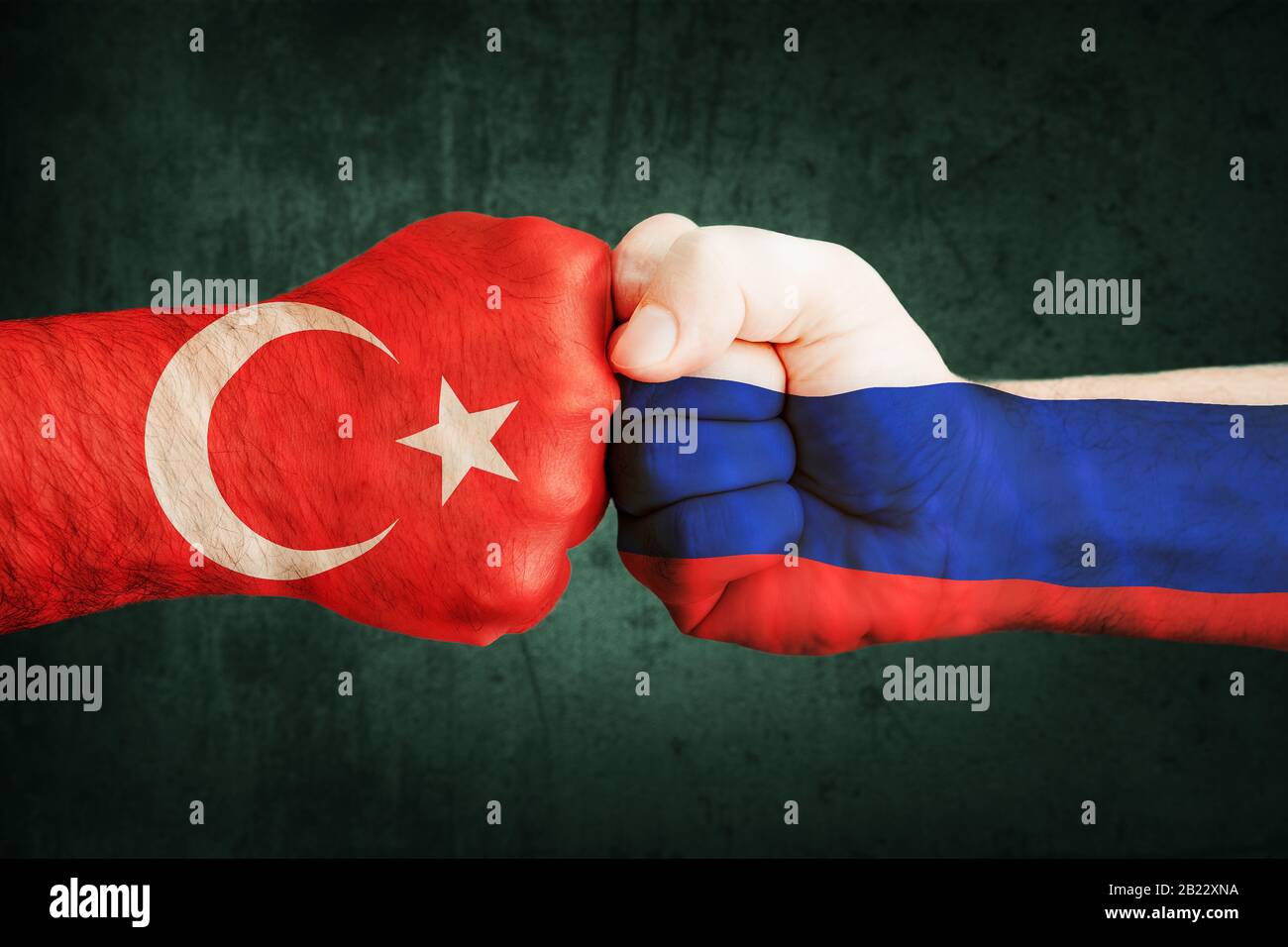 Closeup, bandiere sul pugno della Turchia contro la Siria su uno sfondo nero muro. Concetto di crisi di guerra e conflitti politici tra le nazioni Foto Stock