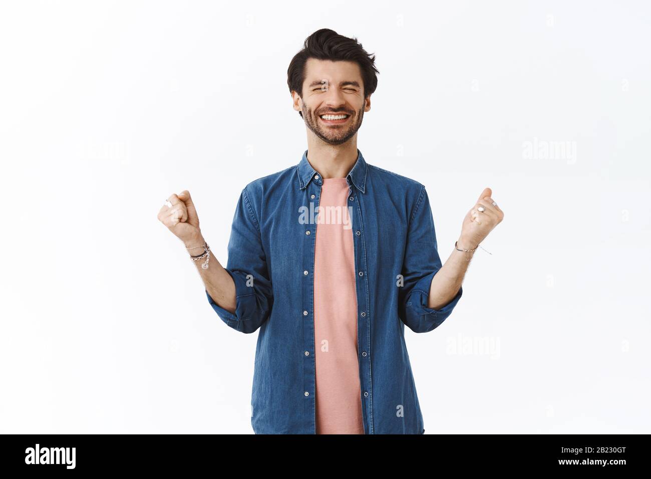 Allegro fortunato bearded uomo vincere molto denaro, pugno pompa e celebrare sorprendente notizie, occhi vicini e sorridente sollevato, finalmente sogno si avverano Foto Stock