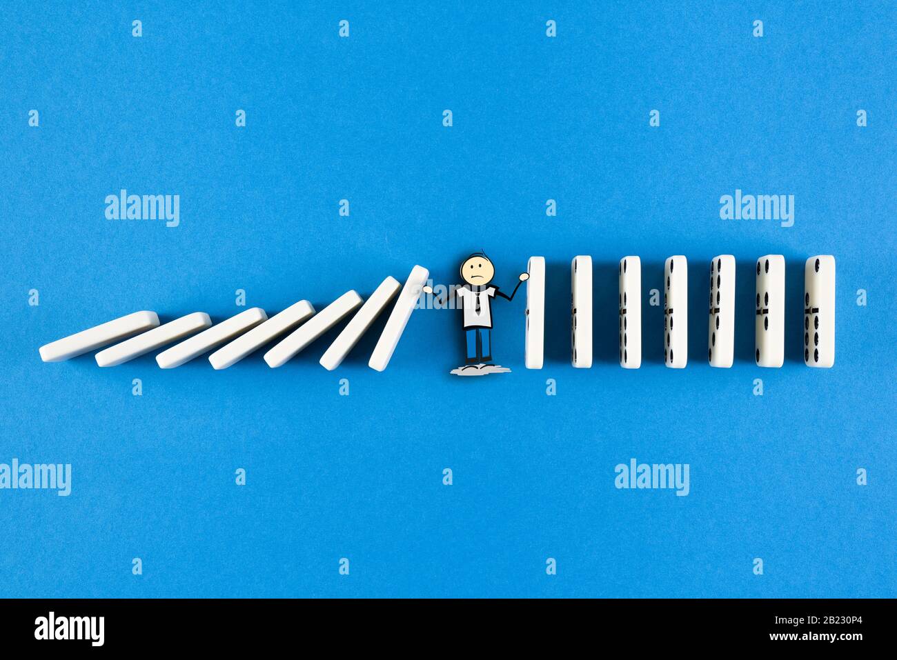 figura stickman che impedisce la caduta della linea di piastrelle domino, effetto domino e concetto di catena di eventi Foto Stock