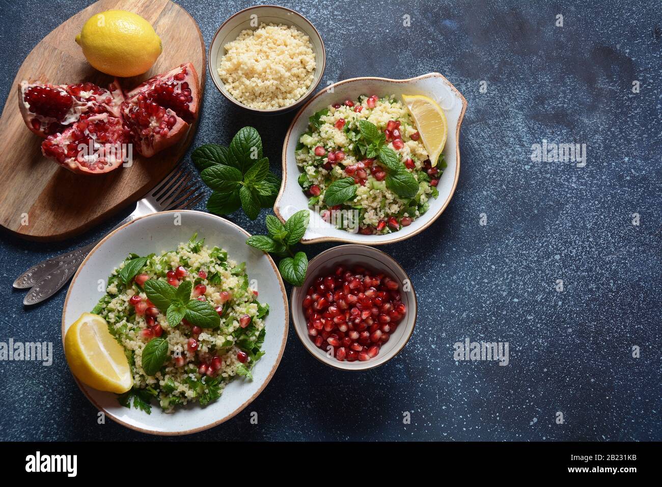 Insalata sana con couscous, menta fresca, cetriolo, melograno, limone e olio d'oliva. Cucina orientale. Concetto di cibo vegano. Cibo tradizionale israeliano Foto Stock