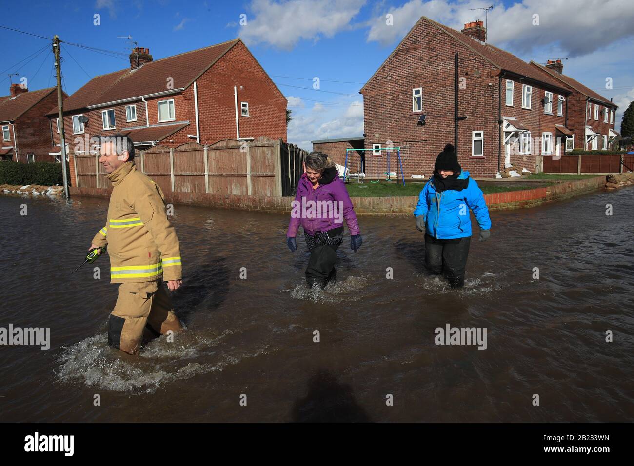 La gente si è fatta strada attraverso le acque alluvionali a East Cowick, nello Yorkshire, dopo forti piogge e forti venti portati da Storm Jorge ha martoriato il Regno Unito durante la notte. Foto Stock