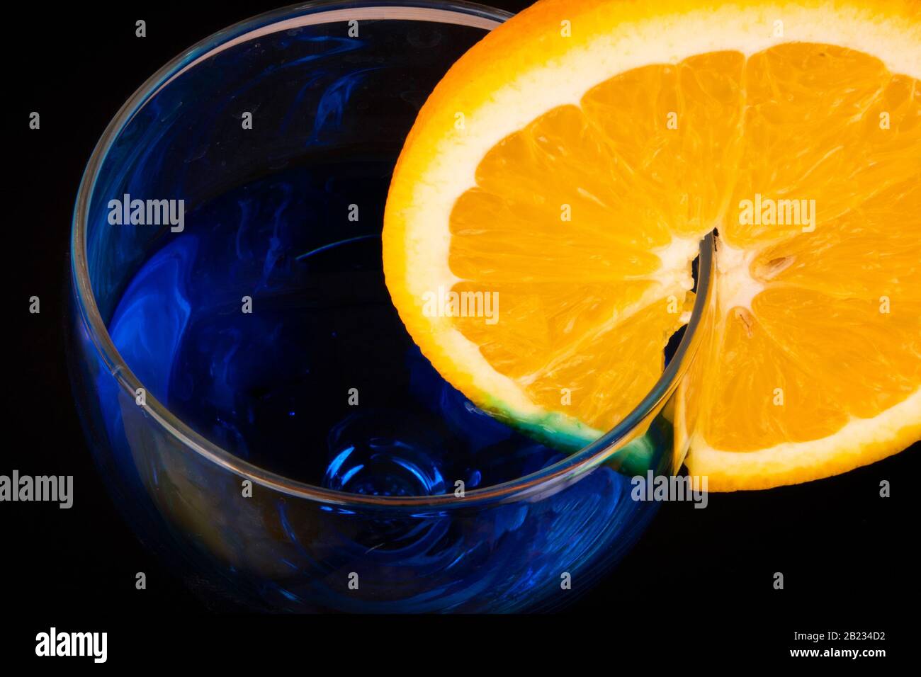 Parte superiore del vetro con bevanda blu e fetta di arancione succosa sul lato Foto Stock