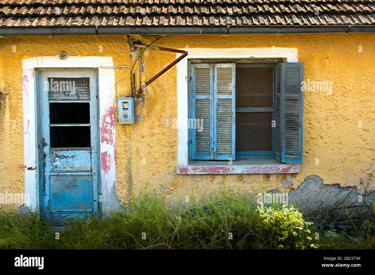 abbandonata, vecchia, casa con piastrelle pareti gialle e vetro rotto Foto Stock