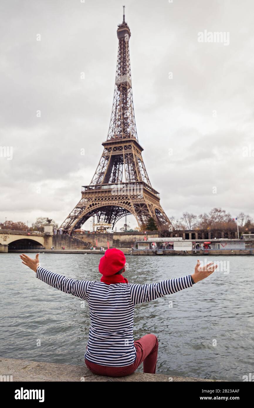 L uomo si trova sulla sponda di un fiume e guarda la Torre Eiffel Foto Stock