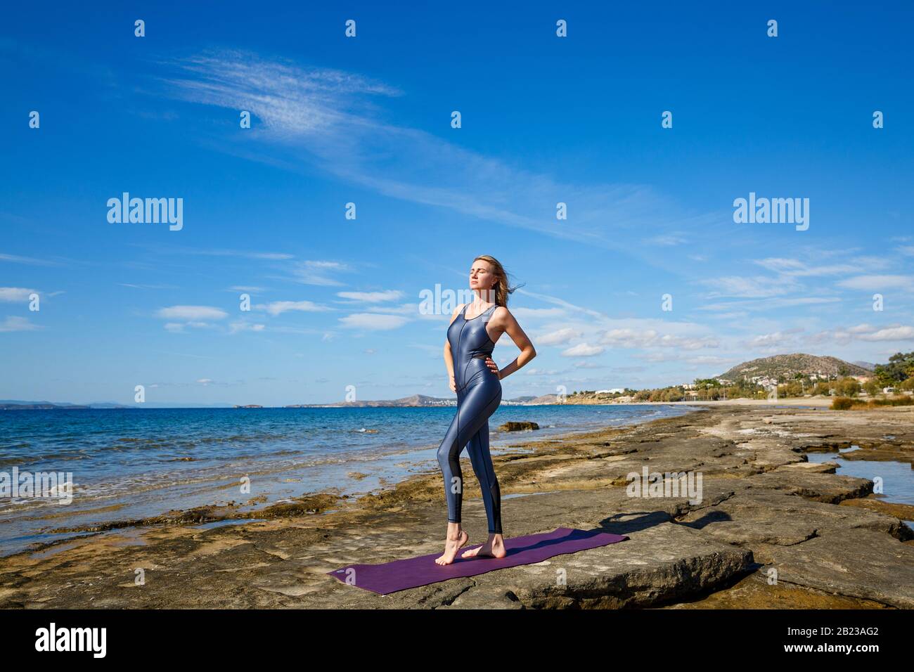 Giovane bella donna in una tuta facendo esercizi sportivi sulla spiaggia. Foto Stock