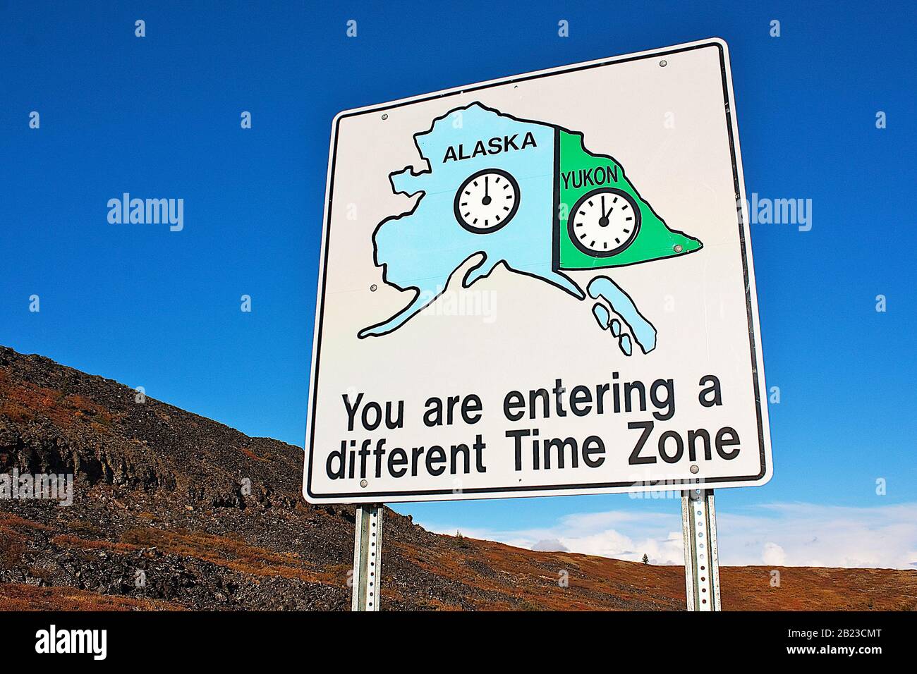 Cartello con informazioni sulla differenza di fuso orario in cima all'autostrada mondiale tra Alaska, Stati Uniti e Yukon, Canada Foto Stock