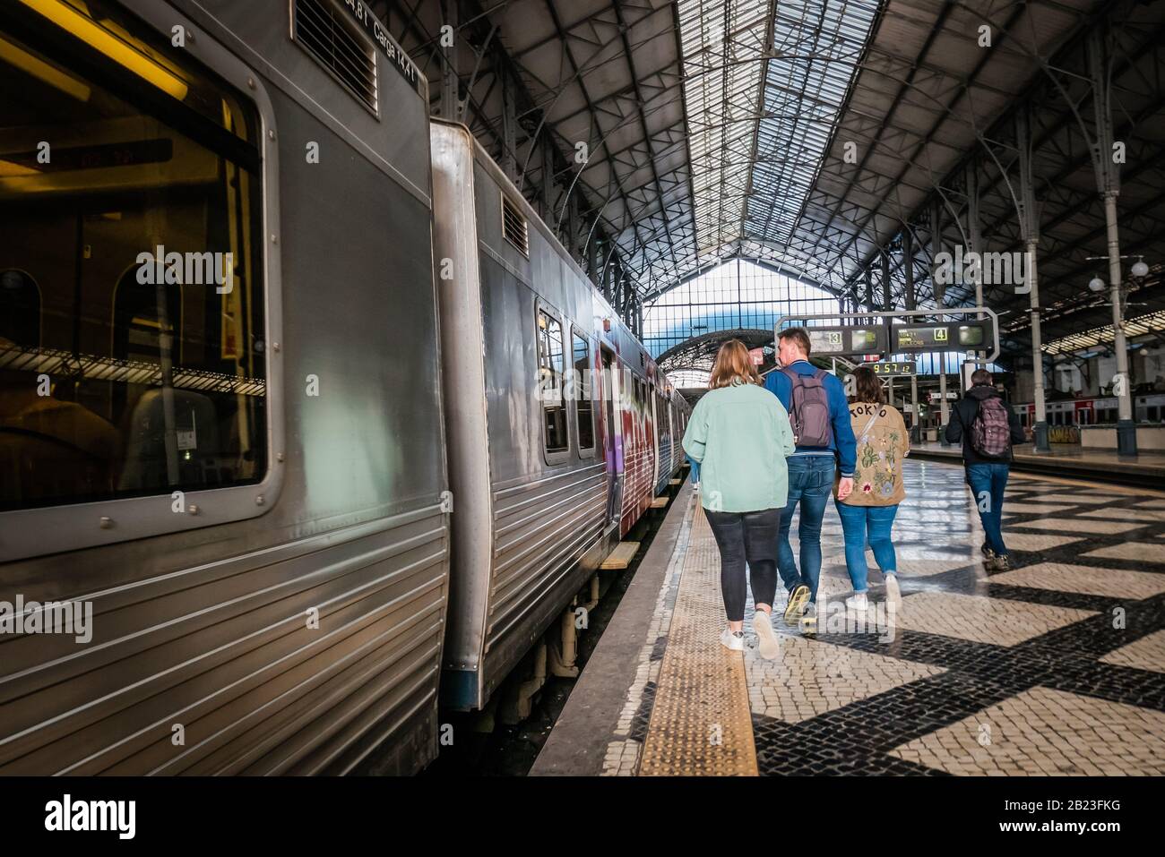 passeggiatori che camminano verso il treno a rossio stazione piattaforma ferroviaria a lisbona portogallo Foto Stock