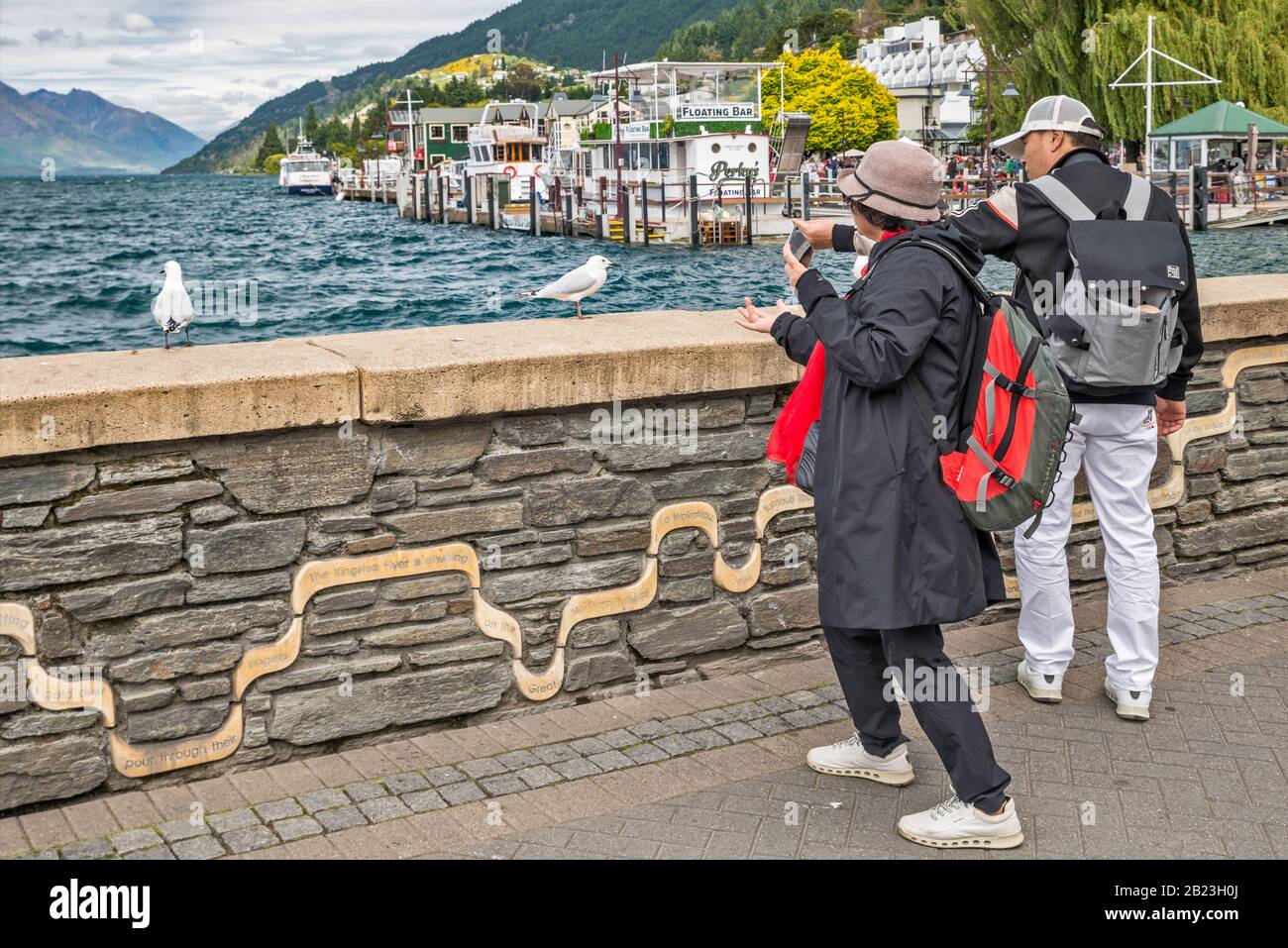 Turisti, gabbiani con fatturazione nera, pontile di Queenstown Bay, lago Wakatipu, Queenstown, Otago Region, South Island, Nuova Zelanda Foto Stock