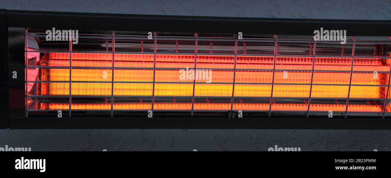 un riscaldatore a infrarossi acceso su una parete della casa Foto Stock