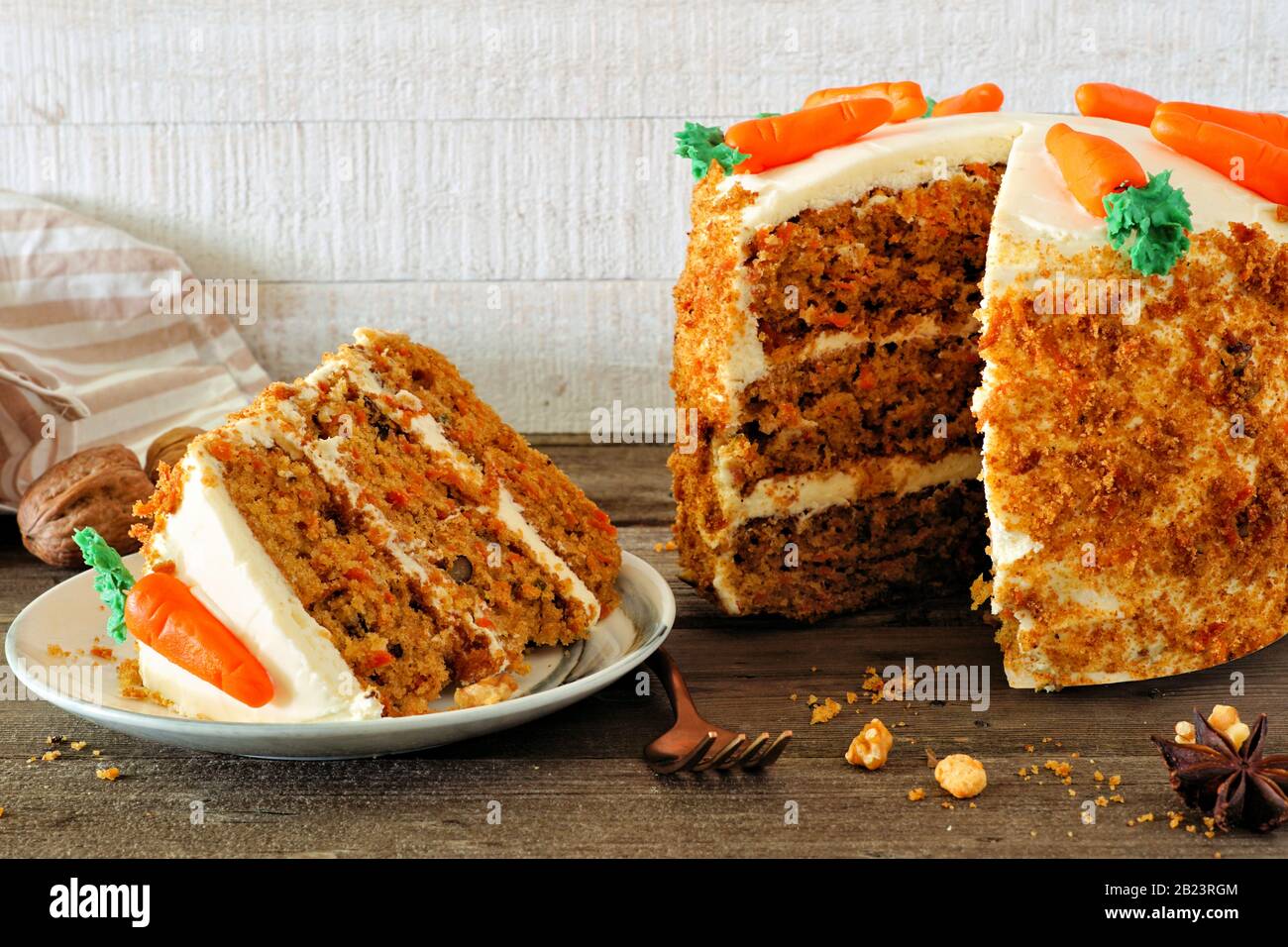Fetta di torta di carote fatte in casa con formaggio cremoso glassante e carote fondenti. Vista laterale scena tavolo con uno sfondo di legno bianco. Foto Stock