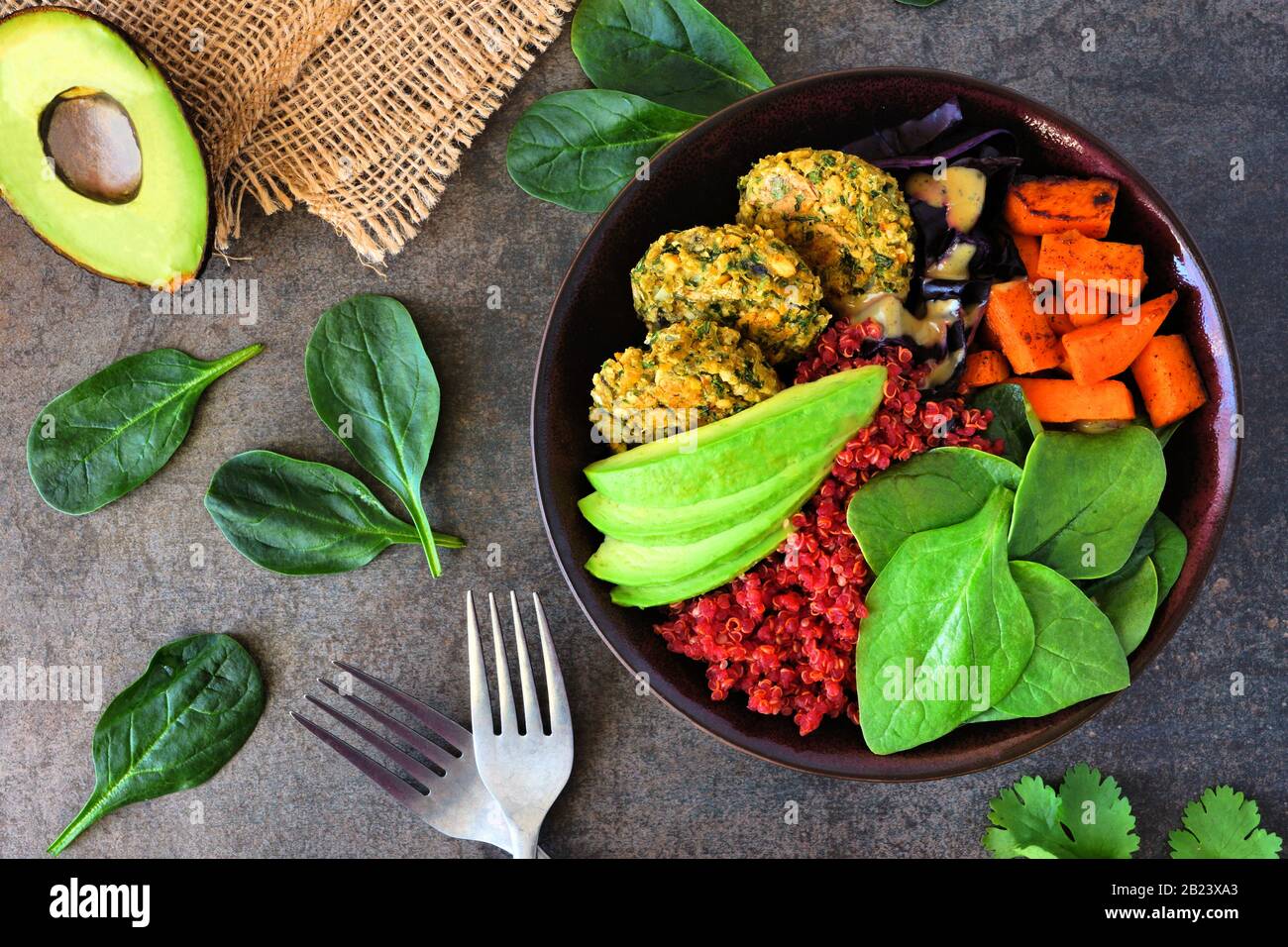 Ciotola sana di buddha vegano con falafel, quinoa di barbabietola, avocado, e verdure su uno sfondo di pietra scura. Concetto di alimentazione sana. Scena aerea. Foto Stock
