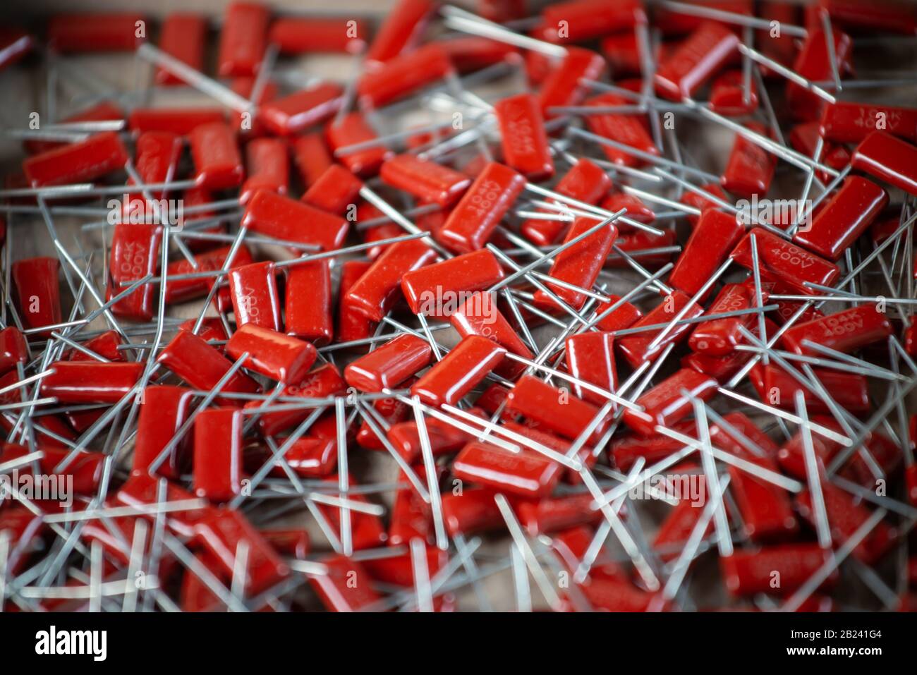 Il primo piano di un gruppo di condensatori rossi si trova l'uno sopra l'altro in una fabbrica di computer e apparecchiature per ufficio. Concetto di parti di qualità. Lotto all'ingrosso Foto Stock