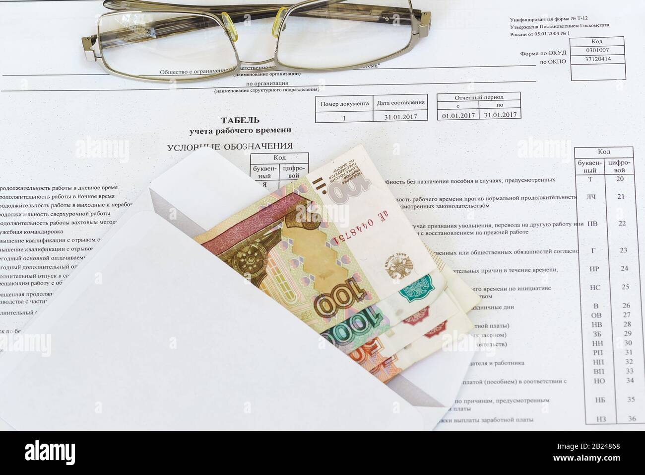 Occhiali e una busta con le fatture ruble che giacciono sul foglio di contabilità dell'orario di lavoro. Il calcolo della remunerazione. Russia Foto Stock