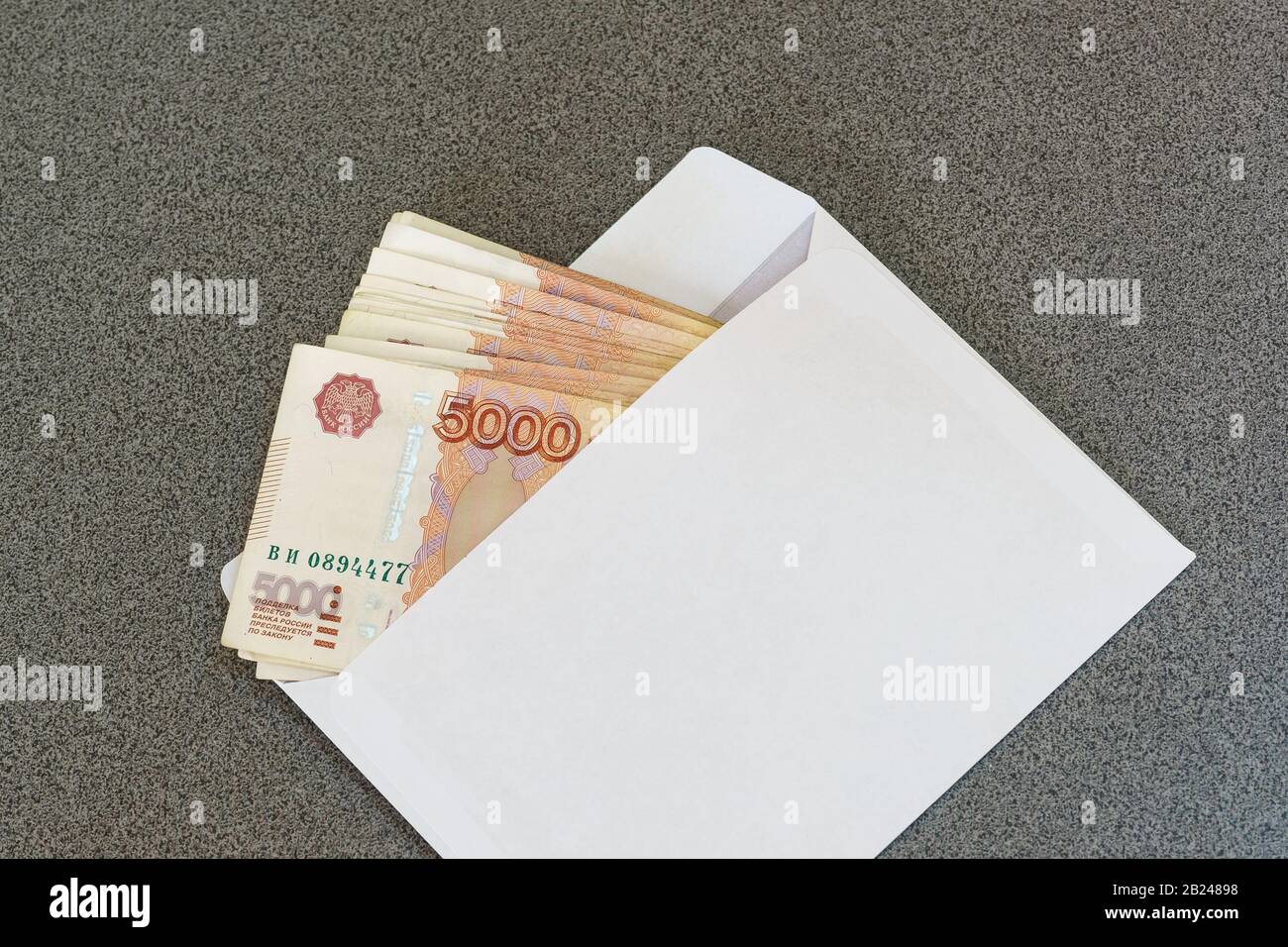Diverse banconote da cinque millesimi rubli in una nuova busta bianca senza una figura adagiata su un tavolo grigio. Russia Foto Stock