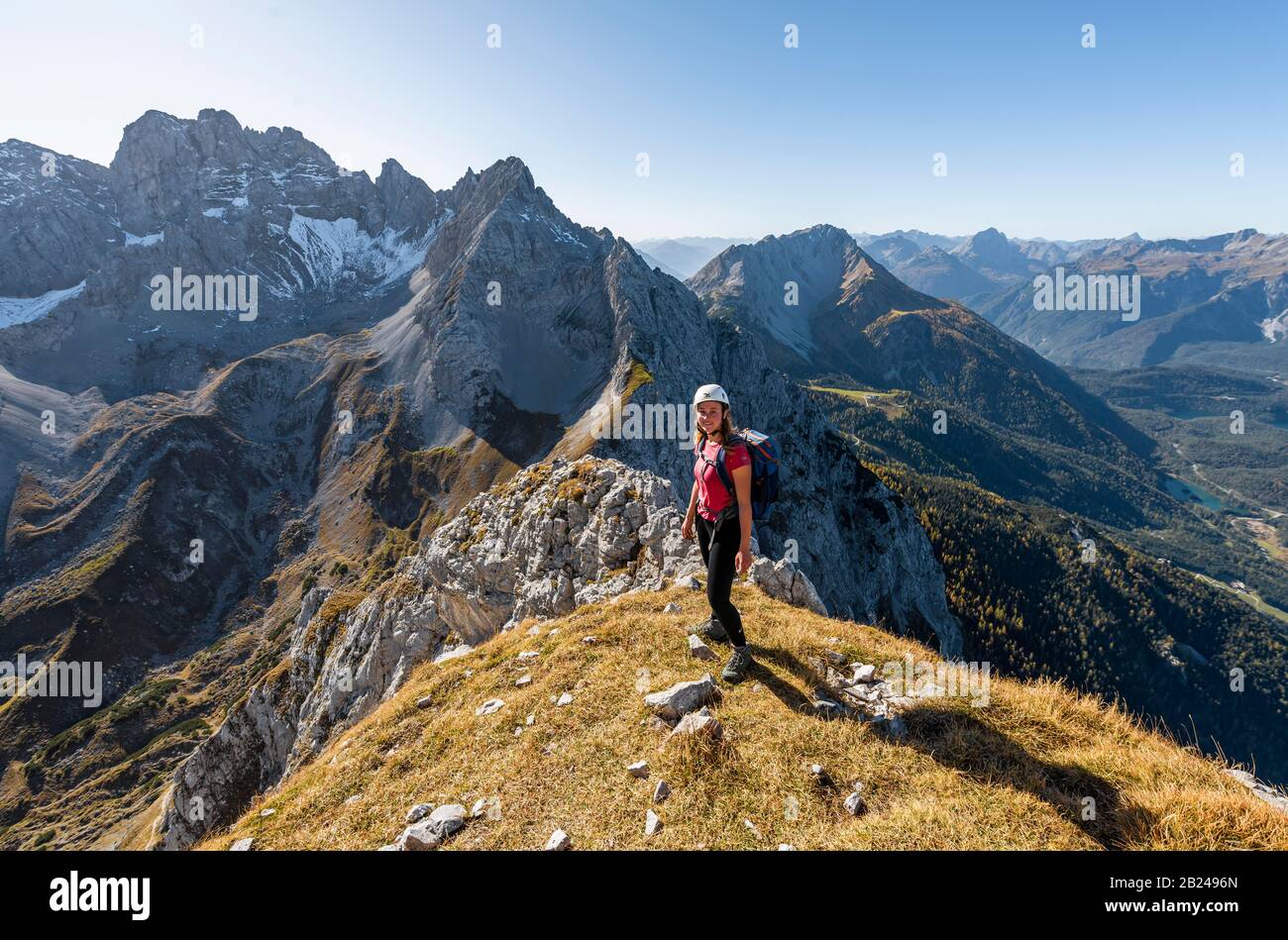 Giovane donna, alpinista con casco da arrampicata guardando il paesaggio di montagna, escursione a Ehrwalder Sonnenspitze, dietro Gruenstein e ovest Foto Stock