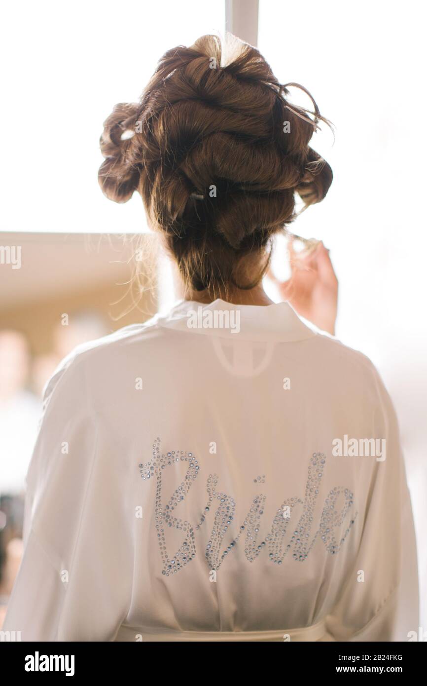 La sposa si prepara al parrucchiere. C'è un vestito bianco su di esso. Foto Stock