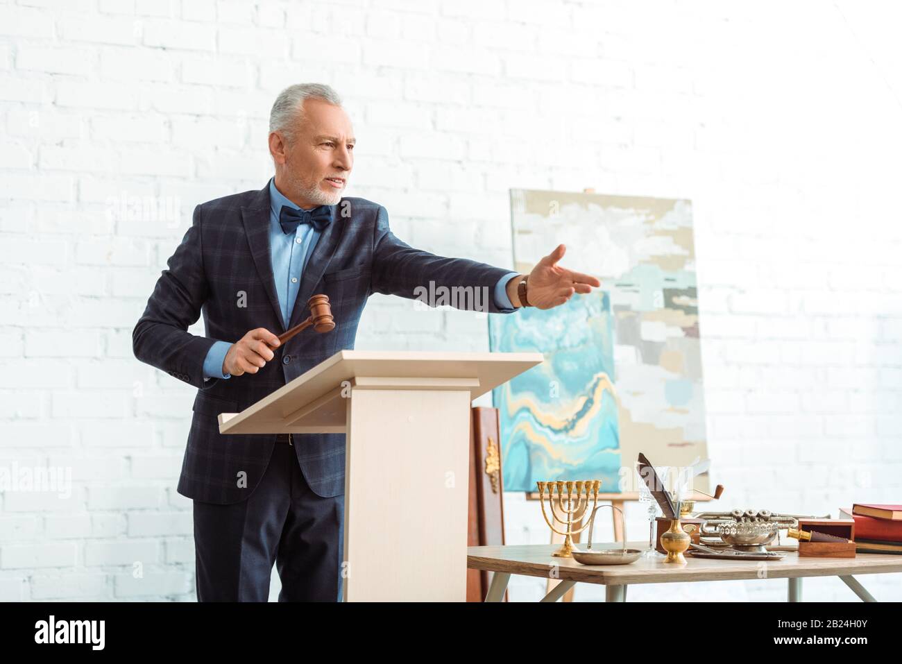 bell'asta che tiene il gavel di legno e punta con la mano durante l'asta Foto Stock