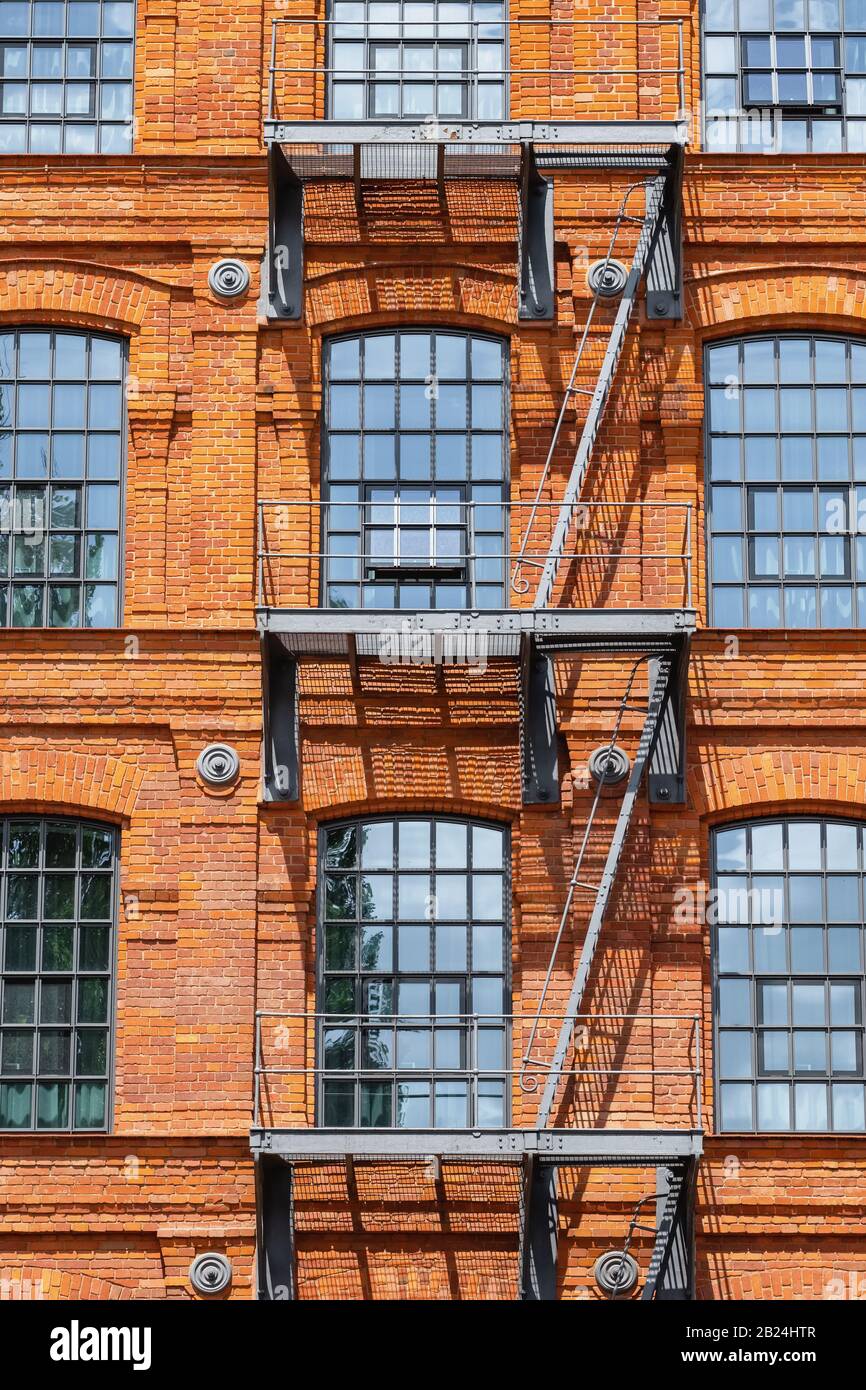 Facciata di un edificio industriale classico in mattoni rossi con scale a scala per la fuga del fuoco Foto Stock