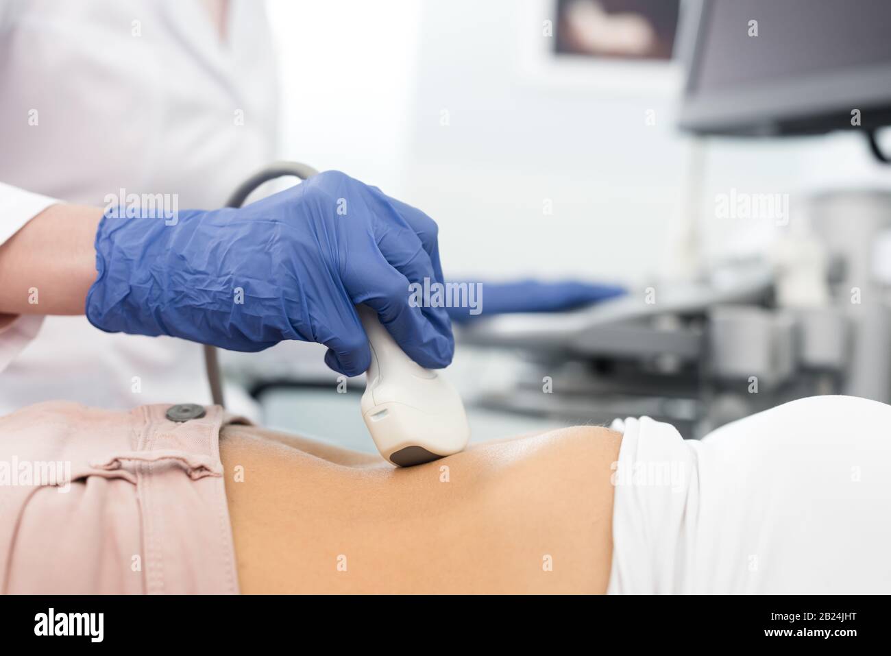 vista ritagliata del medico che esamina lo stomaco del paziente con la scansione a ultrasuoni Foto Stock