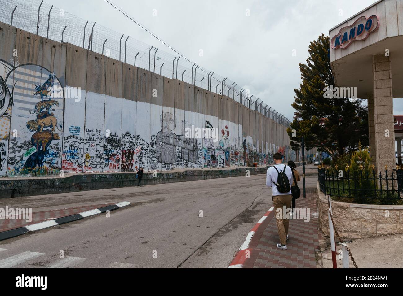 Turisti che camminano vicino alla barriera israeliana della Cisgiordania a Betlemme Foto Stock