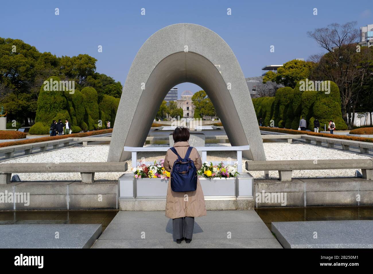 Donna che si trova di fronte al Cenotaph per Le Vittime della bomba atomica (Monumento commemorativo per Hiroshima, Città della Pace) Foto Stock