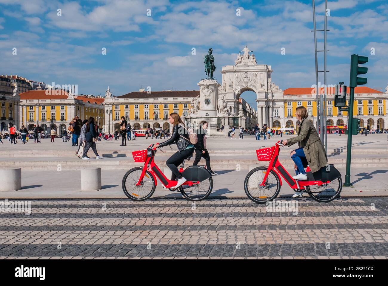 Due ciclisti donne in bicicletta di fronte alla piazza commerciale di Lisbona durante il giorno Foto Stock