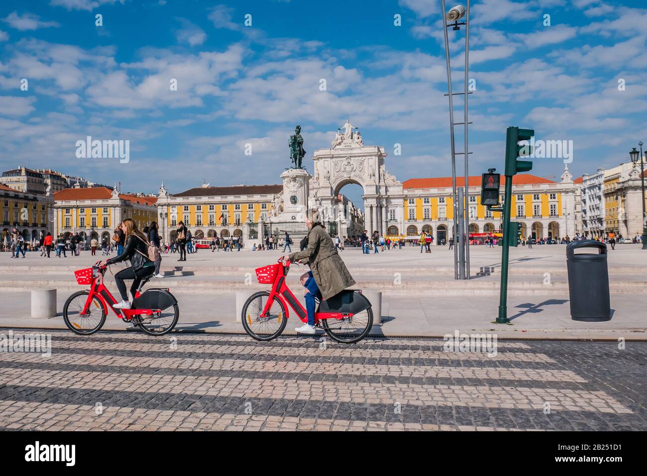 Due ciclisti donne in bicicletta di fronte alla piazza commerciale di Lisbona durante il giorno Foto Stock