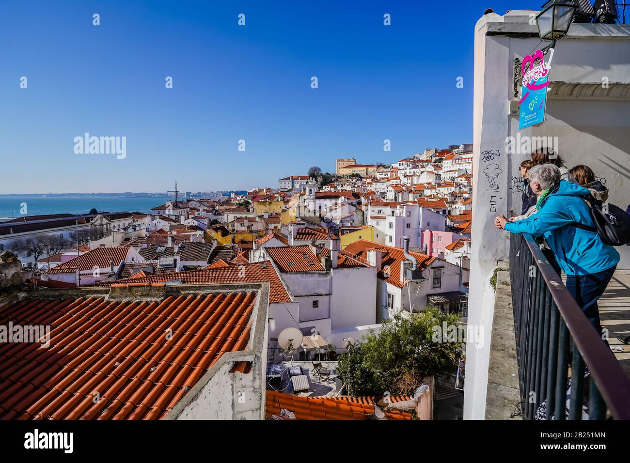 Un gruppo di turisti in un punto panoramico di Lisbona che si affaccia sulla città durante una giornata di sole Foto Stock