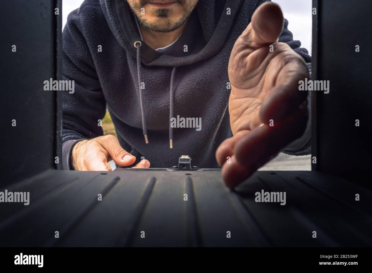 Giovane uomo che raccoglie la sua posta nella mailbox visto dall'interno Foto Stock