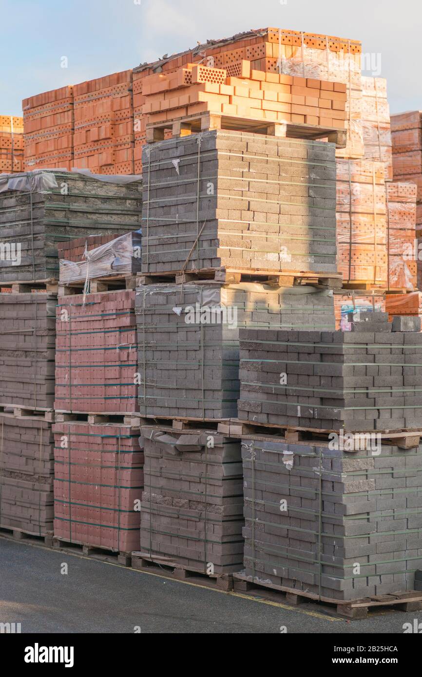 Diversi pallet con mattoni di cemento sovrapposti in magazzino. La produzione industriale di mattoni. foto verticale. Foto Stock