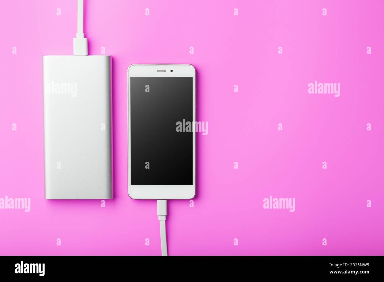 Power Bank carica lo smartphone su uno sfondo rosa. Batteria esterna  universale per gadget spazio libero e composizione minimalista. Carattere  portatile Foto stock - Alamy