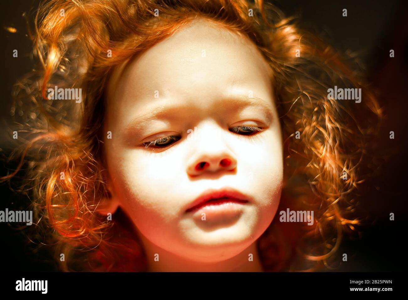 bambina dai capelli rossi con il viso di una bambola con luce solare dura e capelli luminosi. cute fata baby. Foto Stock