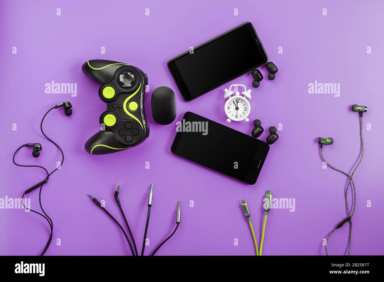 Un pesce smart toothy dai gadget divora il tempo su uno sfondo viola. La creatura sotto forma di vari gadget per smartphone, gamepad e Headpho Foto Stock
