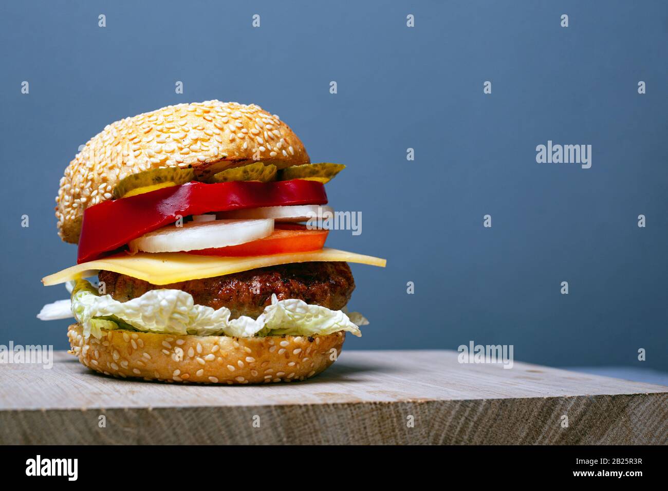 hamburger grande e succoso con spazio copia su sfondo grigio. hamburger doppio con burno di sesamo su una tavola di legno. Foto Stock